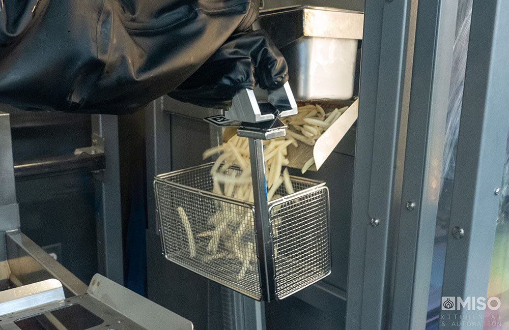 Un robot désinvolte de Miso Robotics rassemblant des frites gelées dans un panier de frire. Roboworx fournira un soutien aux États-Unis