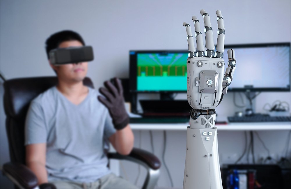 Un homme utilisant la technologie de téléopération pour contrôler une main du robot.